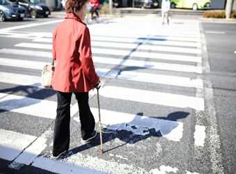 杖を突きながら横断歩道を渡る女性