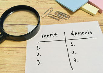 merit、demeritと書かれた紙と虫眼鏡と付箋